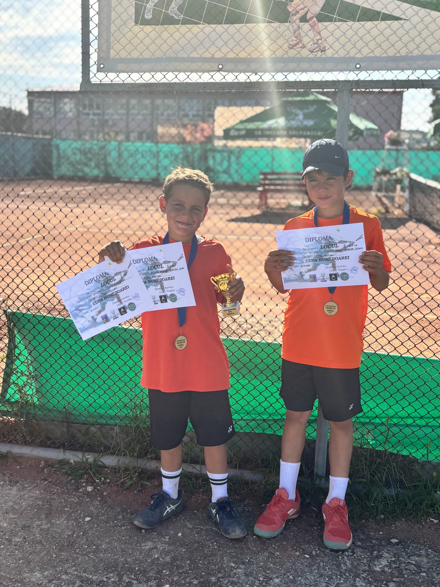 Doi tineri jucători cu diplome la o competiție de tenis